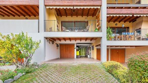 Un immeuble à plusieurs étages doté d’une cour pavée, de balcons en bois et d’un espace d’accueil.