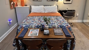 Une chambre d’hôtel avec un lit, un bureau et une chaise, une lampe et des œuvres d’art accrochées aux murs.