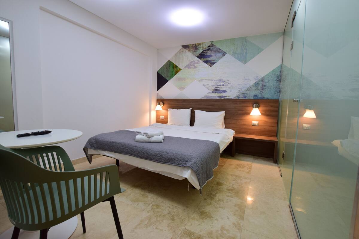 Ein Hotelzimmer mit Bett, Stuhl, Tisch und Wand mit geometrischem Muster.