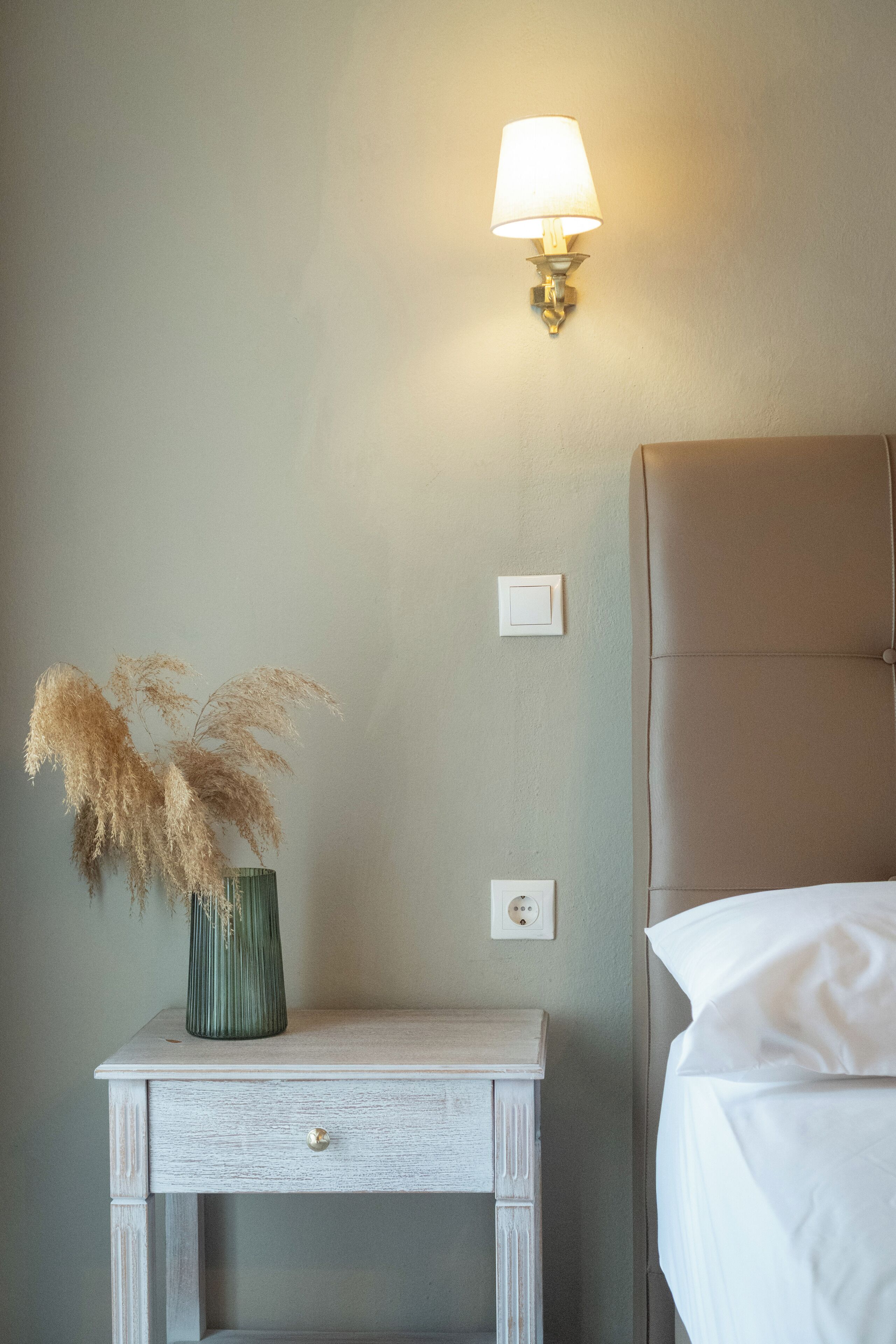 A bedroom with a bedside table, a lamp, and a bed.