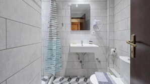 Et moderne badeværelse med bruser, toilet, vask og spejl.