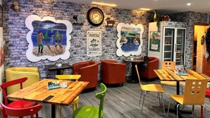 A cozy restaurant with brick walls, colorful chairs, and a wooden table. - Loch Ness Gate House (Fort Augustus)