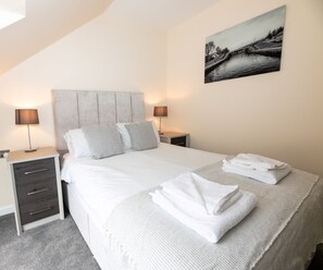 Relax in a serene space with a neatly made bed, bedside table, and wall art.