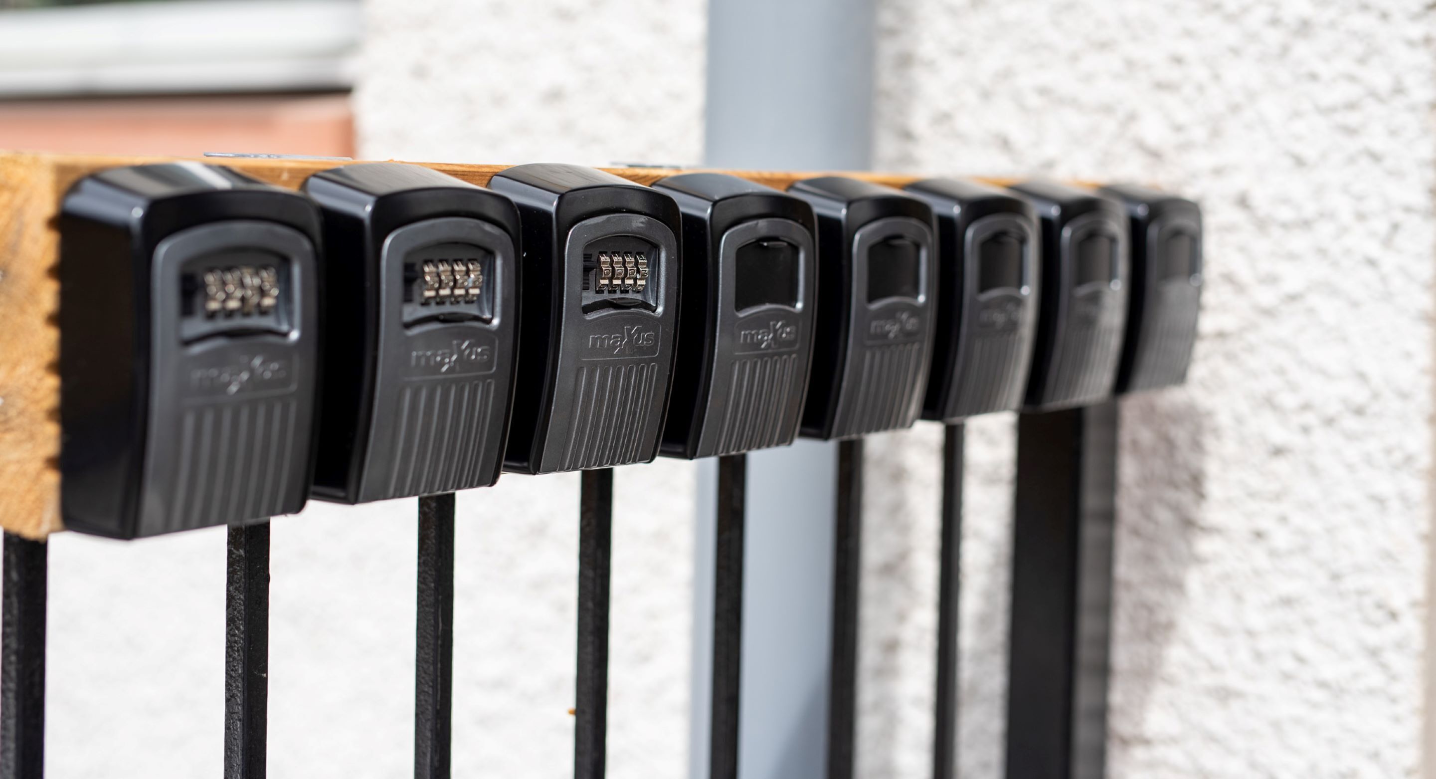 Een rij zwarte beveiligingscamera's bevestigd aan een houten leuning tegen een structuurwand.