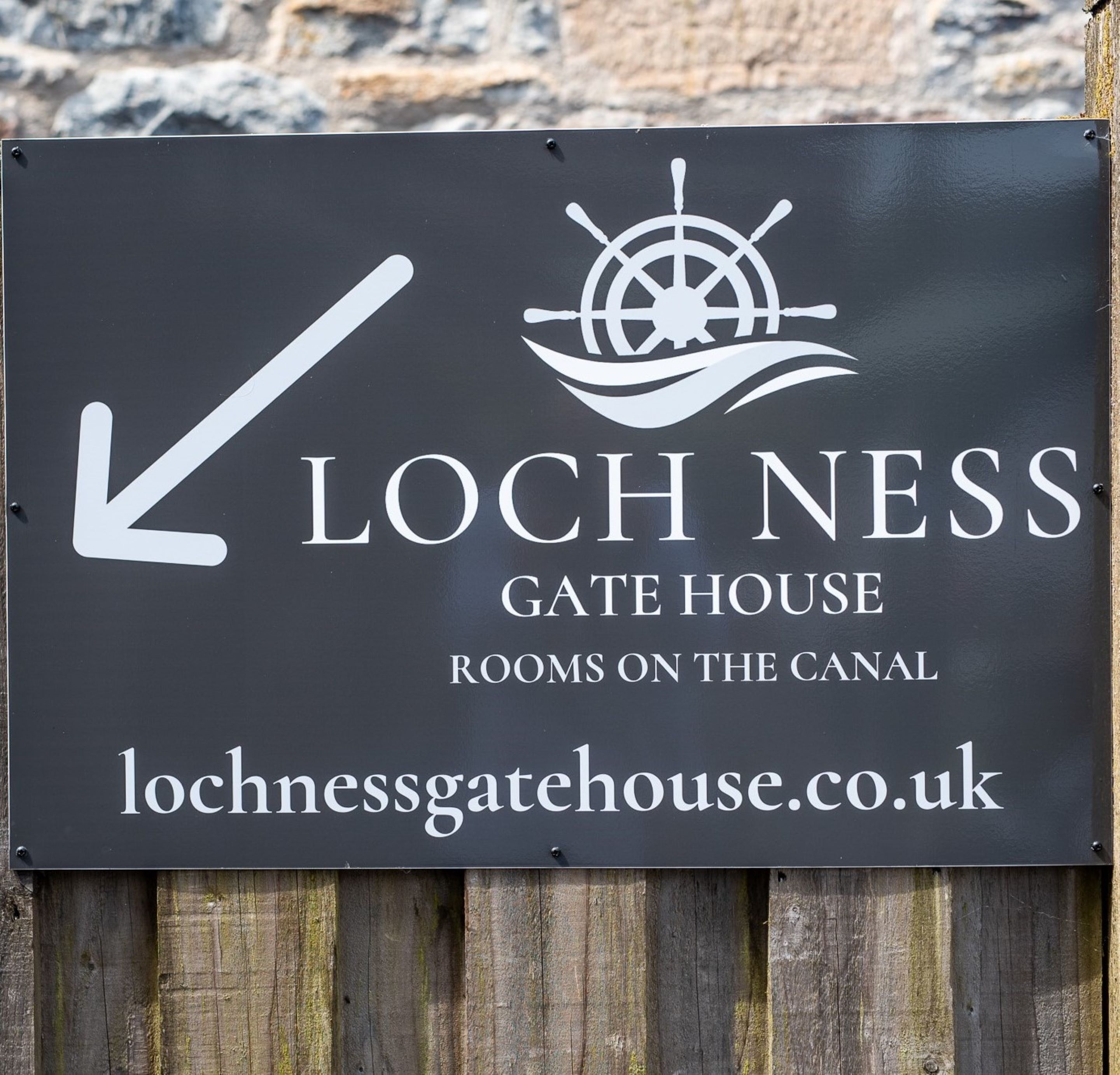 Señal del Loch Ness Gate House con una flecha indicando la ubicación de las habitaciones en el canal.