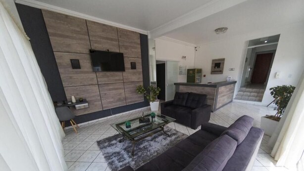 A modern living room with a sofa, a coffee table, and a TV mounted on the wall. - Nacional Park Hotel Lages (Lages)