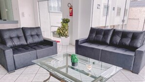 A modern living room with two grey sofas, a glass coffee table, and a potted plant. - Nacional Park Hotel Lages (Lages)
