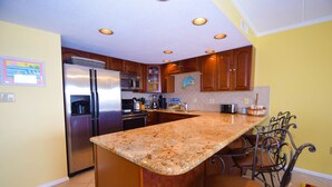 Una cocina con encimeras de granito, electrodomésticos de acero inoxidable y gabinetes de madera.