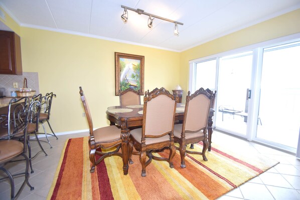 A dining area with a wooden table and chairs, a colorful striped rug, and a painting on the wall. - Harbour Island 304K-Baywater 14th St, WIFI, Pool, Elev, W/D, AC (Ocean City)