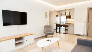 A modern living room with a flat-screen TV, a white coffee table, and a grey sofa. - Cozy and spacious apartment in Zografou (Zografos)