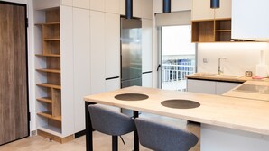 A modern kitchen with a central island, built-in shelves, and a stainless steel refrigerator. - Cozy and spacious apartment in Zografou (Zografos)