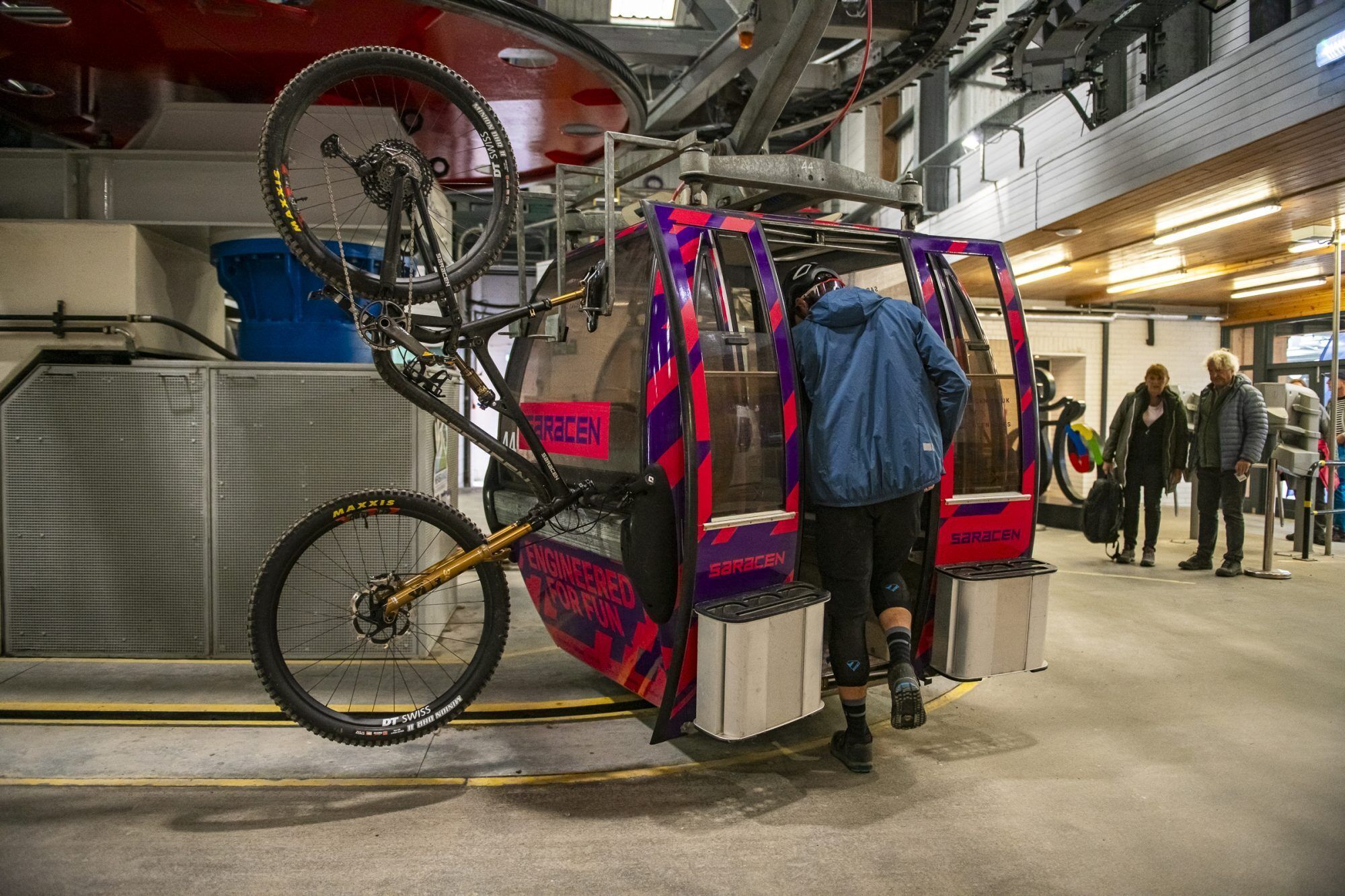 A bicycle mounted on a platform with a person standing beside it.