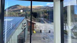A view from inside a building looking out to a parking area with a mountain in the background. - Base Camp Hotel Nevis Range (Fort William)