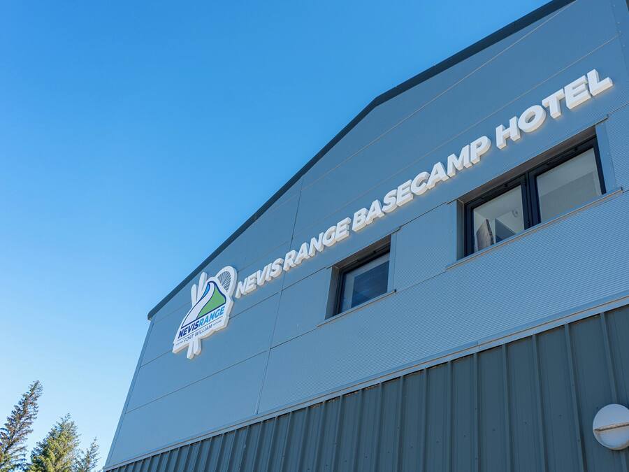 The exterior of the Nevisrange Basecamp Hotel with a clear sky in the background.