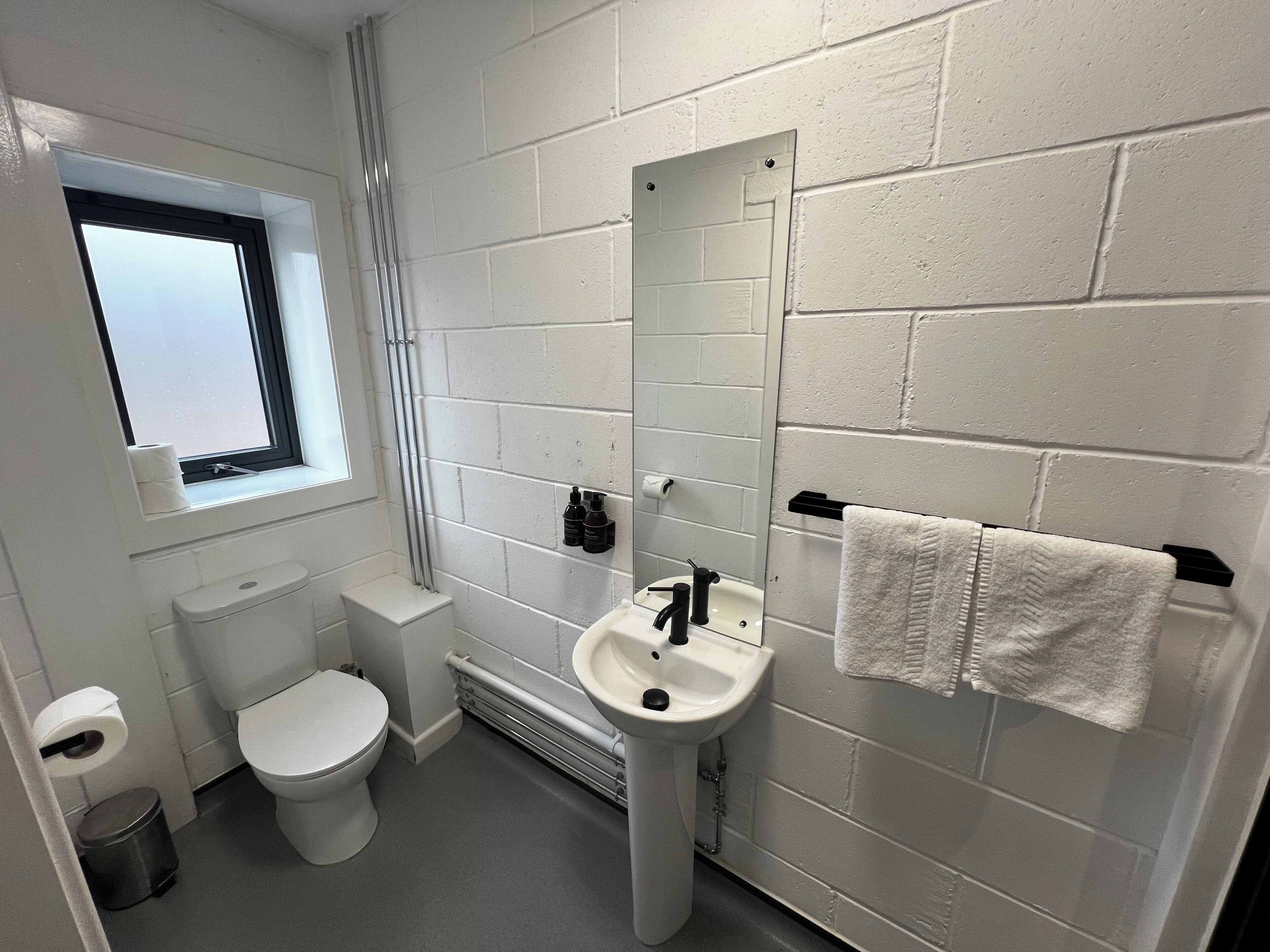 A small, clean bathroom with a toilet, sink, and window.
