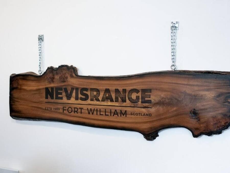 Un letrero de madera con el texto "NEVISRANGE ESTD 1989 FORT WILLIAM SCOTLAND".