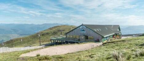 Ein rustikales Blockhaus mit geneigtem Dach, einer Veranda und Blick auf die umliegende Landschaft.