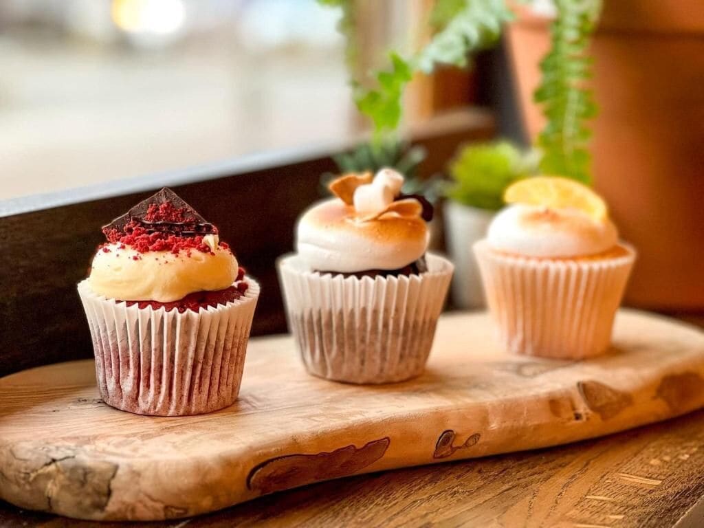 Three cupcakes on a wooden board.