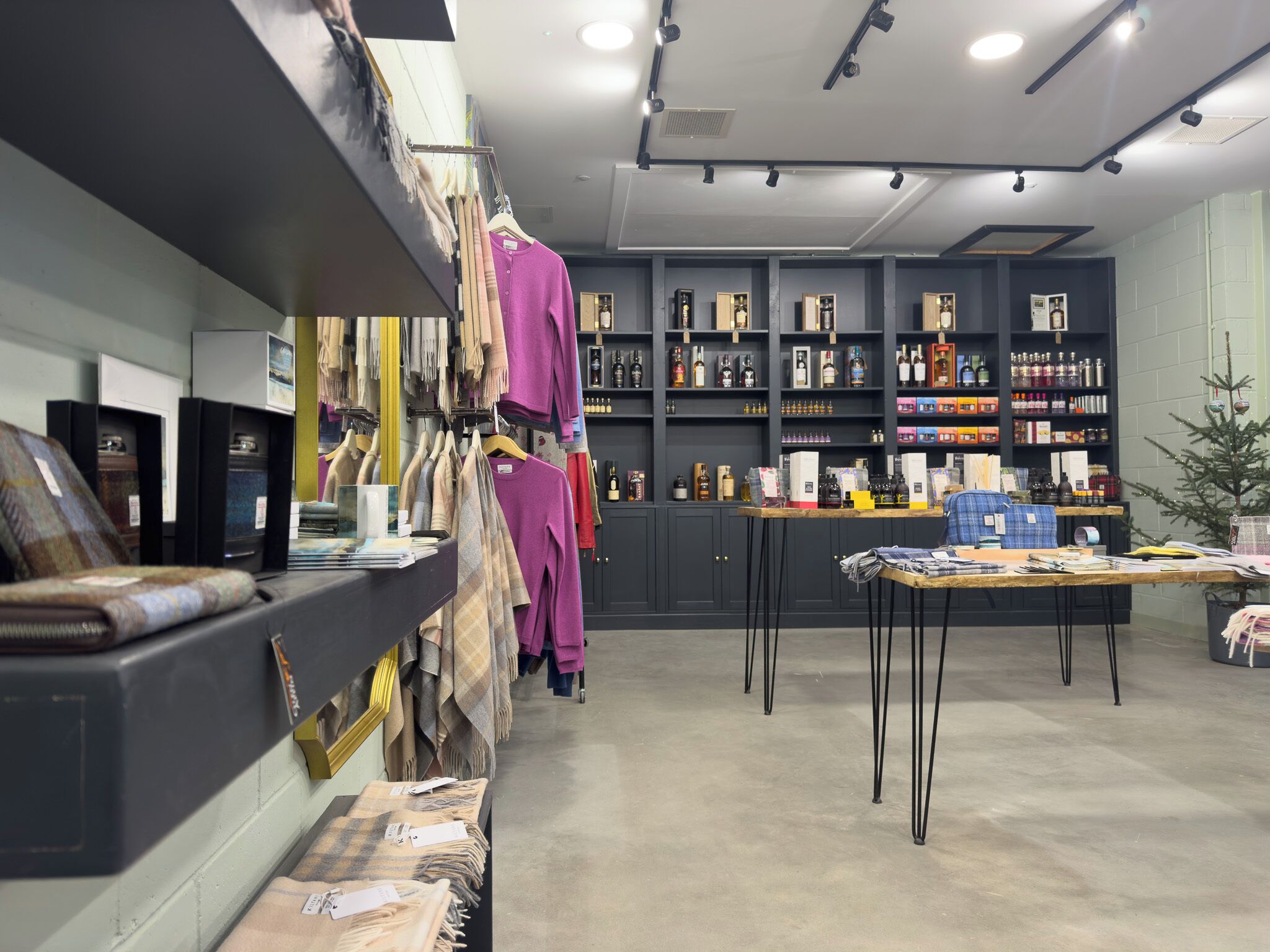 Un magasin de détail avec des étagères remplies de divers produits, une table d’exposition présentant différents articles et un mur où sont accrochés des produits.