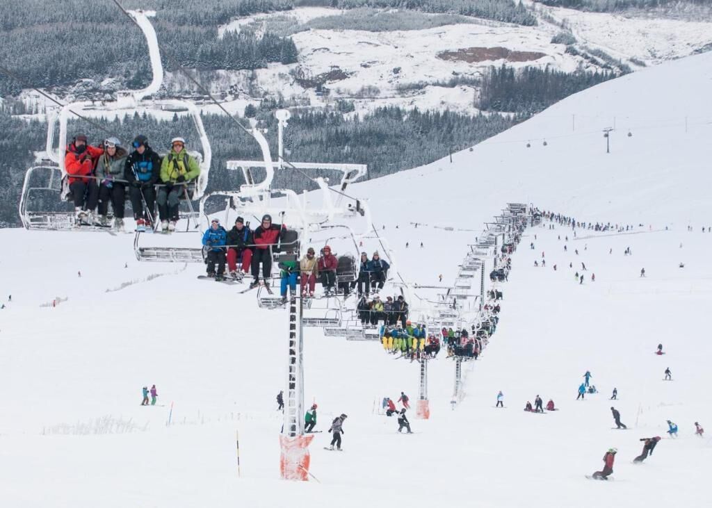 Un télésiège avec des skieurs qui descendent la piste.