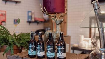 Una mesa de madera con cuatro botellas de Glen Spean Brewing Co. Snowgoose IPA y una cabeza de venado decorativa con una pantalla roja.