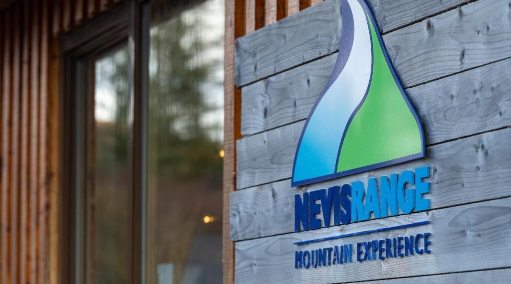 Ein Holzschild mit dem Logo und dem Namen "NEYSRANCE" und dem Slogan "MOUNTAIN EXPERIENCE".
