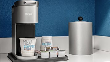 A Keurig coffee maker with disposable coffee cups and pods on a countertop.
