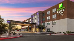 Un bâtiment de la chaîne Holiday Inn Express & Suites, doté d’une entrée couverte, arborant le drapeau américain et disposant d’un parking.