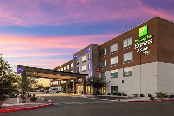 A Holiday Inn Express & Suites building with a covered entrance, American flag, and a parking lot. - Holiday Inn Express & Suites Phoenix West Tolleson by IHG (Phoenix)