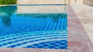 Une piscine dont le bord est revêtu de carrelage et qui est équipée d’une main courante en métal.