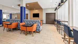 Un espace repas moderne avec des banquettes et des tables, un plancher en bois et un téléviseur à écran plat fixé au mur.