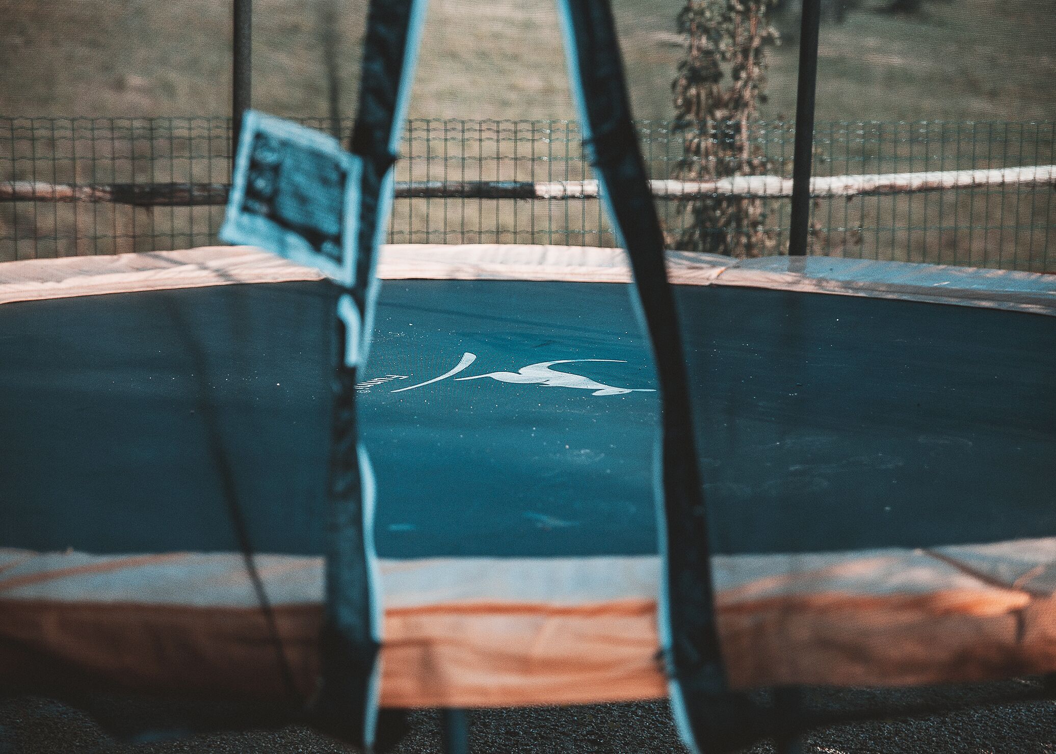Un trampoline doté d’un filet de sécurité et d’une surface bleue.