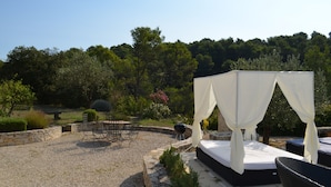 An outdoor seating area with a white canopy, a stone bench, and a grill. - Stone house with beautiful swimming pool and enchanting panorama (Seguret)