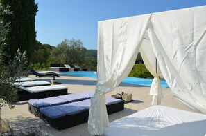 Uma área à beira da piscina com espreguiçadeiras e um toldo.