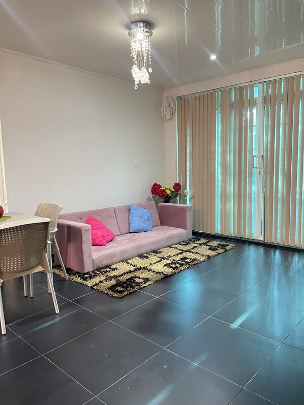 Ein modernes Wohnzimmer mit einer Couch, einem Esstisch und einer Pendelleuchte.