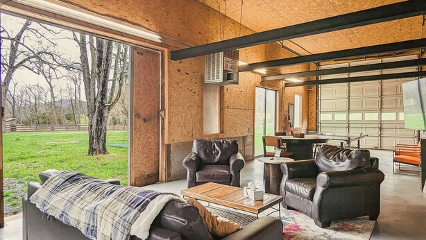 Ein geräumiges Wohnzimmer mit großem Fenster, Ledersofas und Holzboden.