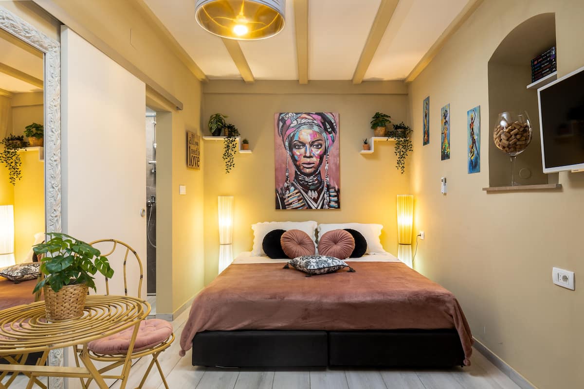 Un dormitorio con una cama grande, lámparas de noche, un televisor montado en la pared y un cuadro.