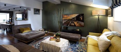 Uma sala de estar moderna com um sofá, uma mesa de centro e uma área de jantar com mesa e cadeiras.