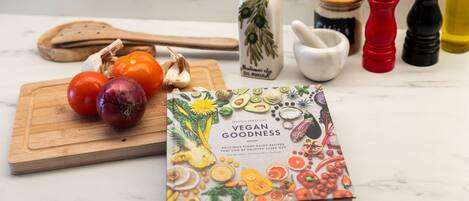 Un libro titulado 'Vegan Goodness' con una variedad de verduras sobre una tabla de cortar.