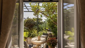 A conservatory with a table and chairs, surrounded by potted plants and a pergola. - Dubrovnik Old Town Apartments (Dubrovnik)
