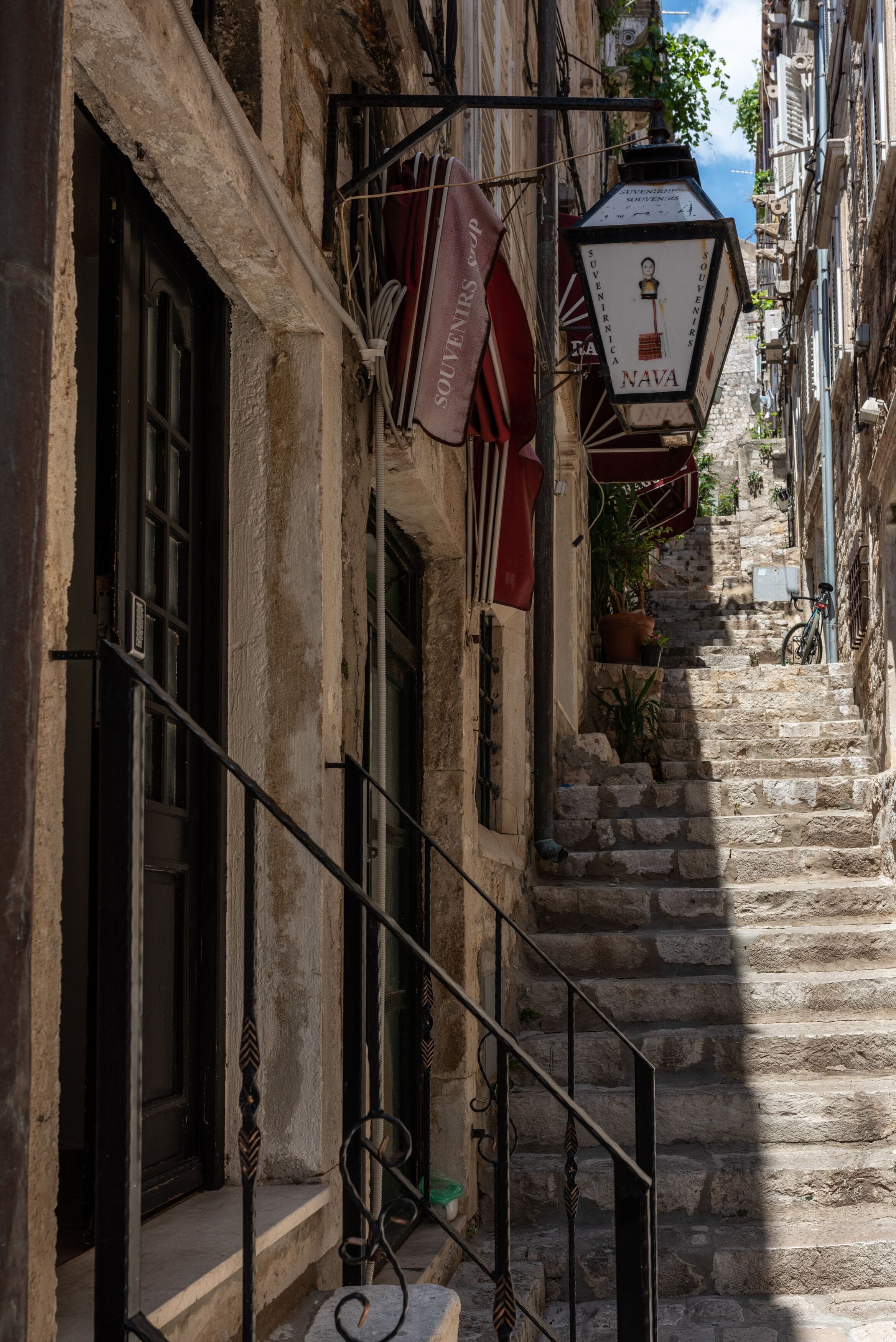 A narrow stone staircase leading to a building with a sign reading "NAVA".