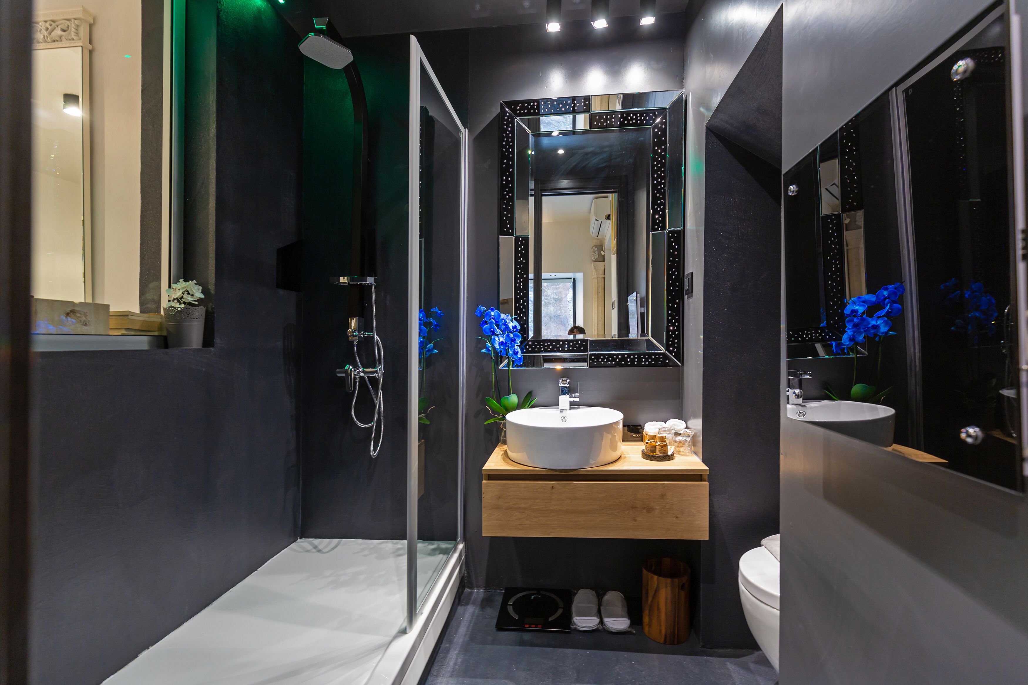 A modern bathroom with a large mirror, a white sink, and a shower area.