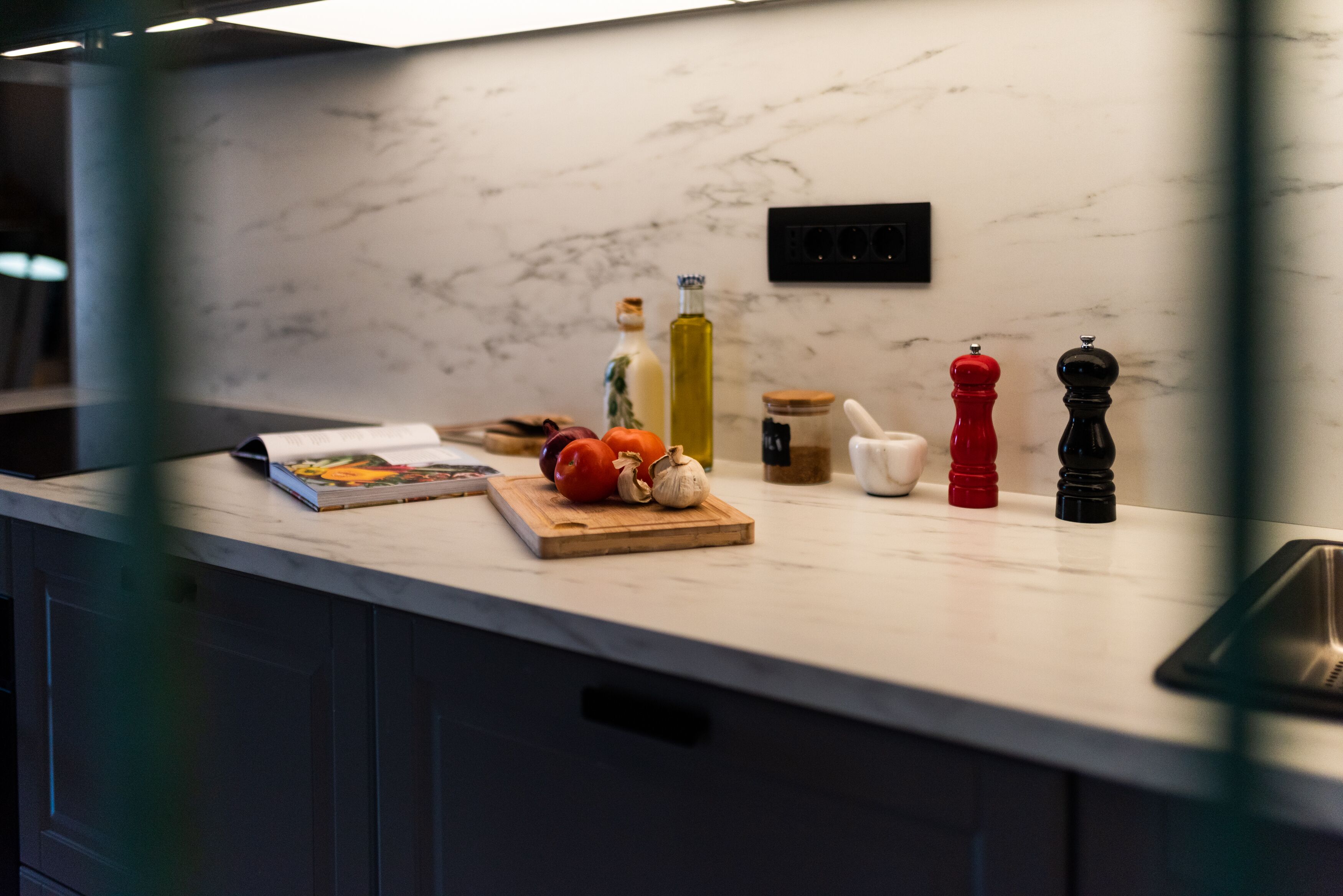 A kitchen counter with a marble backsplash, a cutting board with vegetables, and various kitchen items.