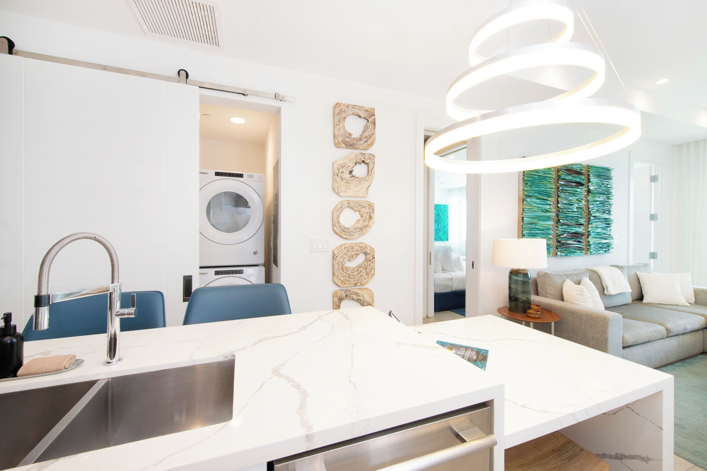 A modern kitchen with a built-in washing machine, a marble countertop, and a stylish pendant light.