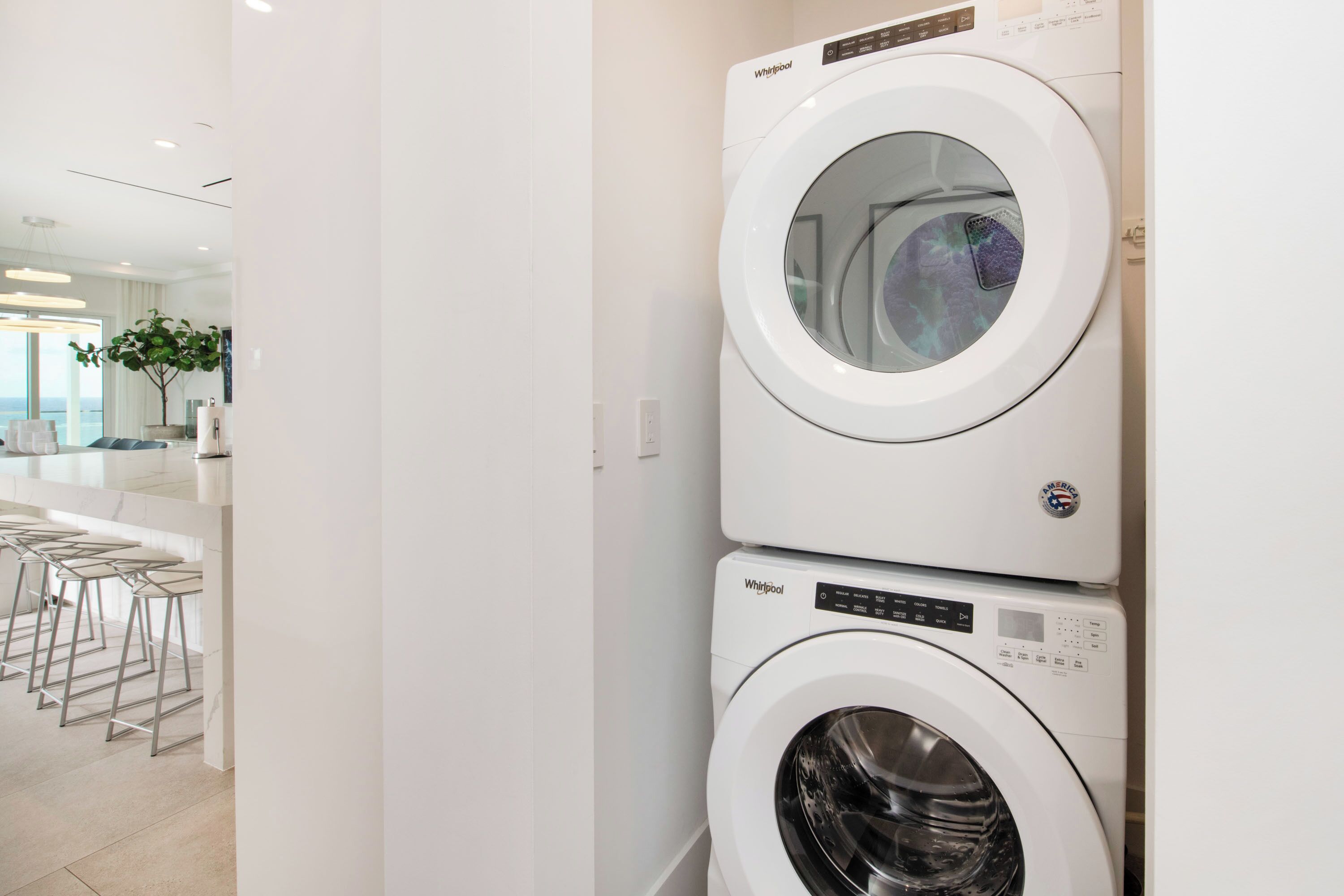 Uma lavanderia moderna com duas máquinas de lavar Whirlpool empilhadas.