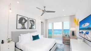 Een moderne hotelkamer met een groot bed, een bureau en uitzicht op zee.