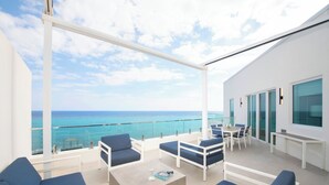 Een modern balkon buiten met blauwe zithoek, een tafel en uitzicht op de oceaan.
