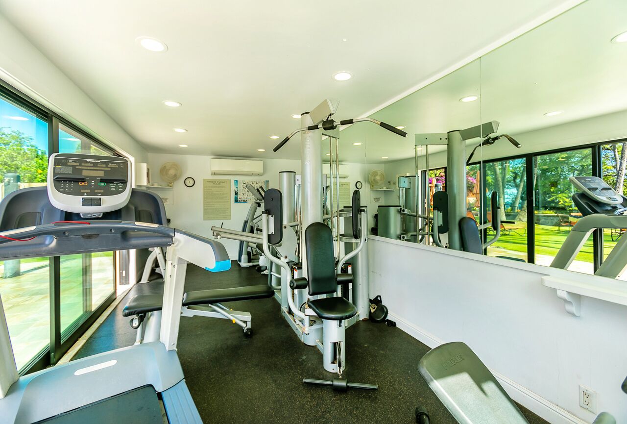 A modern gym with cardio equipment, weight machines, and a large mirror.