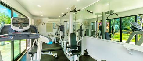 A modern gym with cardio equipment, weight machines, and a large mirror.