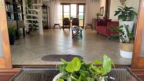 Amplia sala de estar con un gran ventanal, un sofá rojo, una mesa de centro y una planta en maceta.